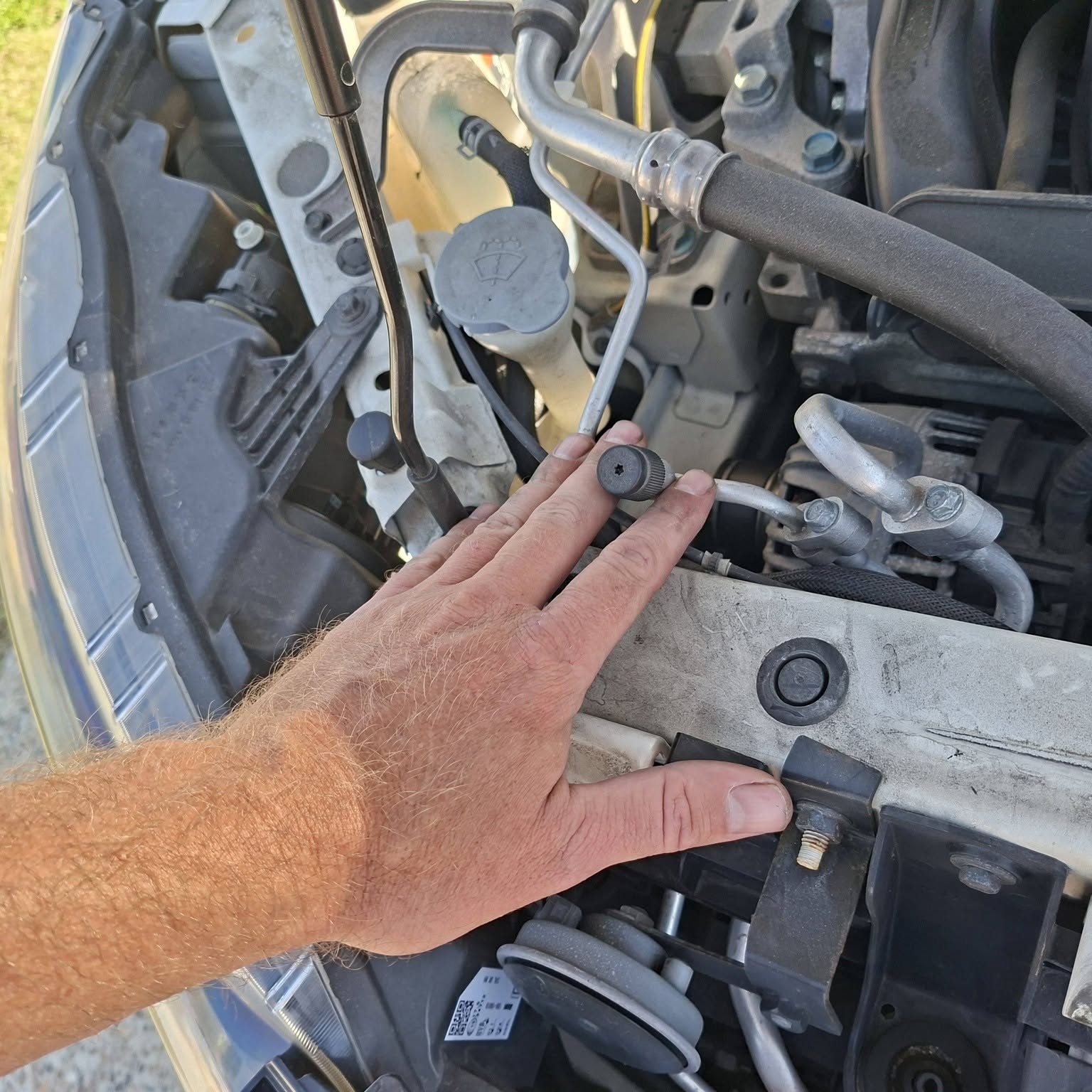 Roy checking an air conditioning line in an engine bay